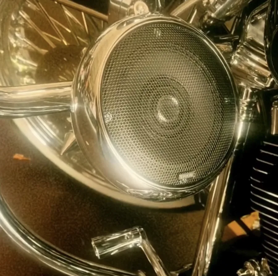 Close-up of a chrome AMS Pod with a mesh grille mounted on the crash bar of a Harley-Davidson Road King
